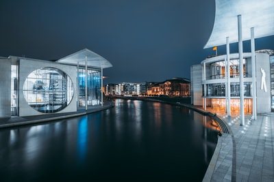 白色和棕色的水域附近的混凝土建筑在夜间
